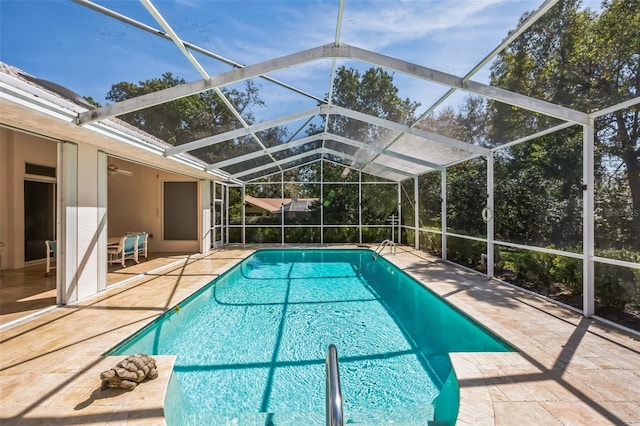 outdoor pool with glass enclosure, a patio, and a ceiling fan