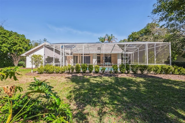 back of property featuring glass enclosure and a yard