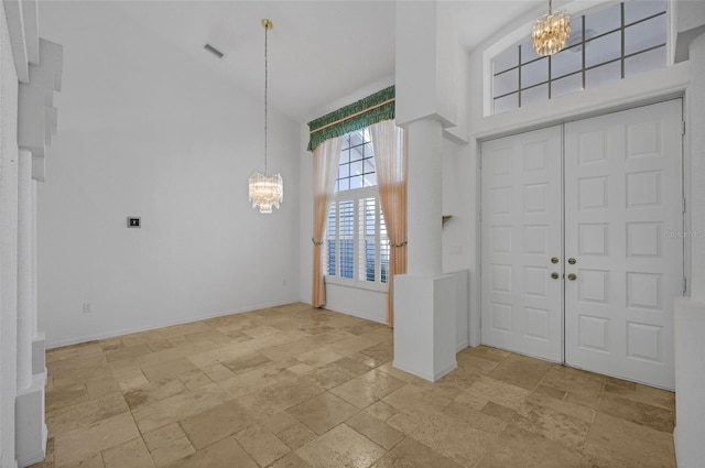 foyer entrance featuring high vaulted ceiling, stone tile floors, visible vents, and a notable chandelier