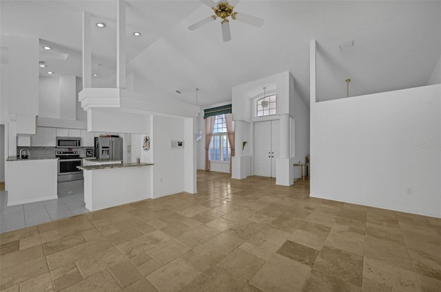 kitchen with appliances with stainless steel finishes, white cabinetry, high vaulted ceiling, and a peninsula