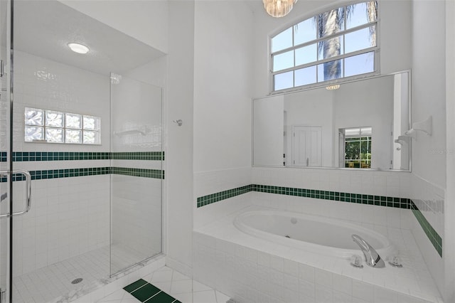 full bathroom featuring a towering ceiling, a stall shower, tile patterned flooring, and a bath