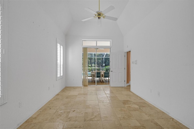 empty room featuring a sunroom, ceiling fan, high vaulted ceiling, and stone tile flooring