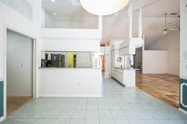 unfurnished living room with high vaulted ceiling, visible vents, ceiling fan, and light tile patterned floors