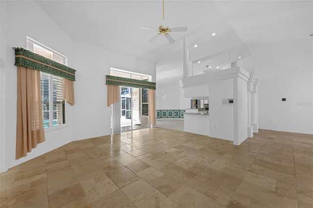 unfurnished living room featuring a towering ceiling, ceiling fan, stone tile flooring, and recessed lighting