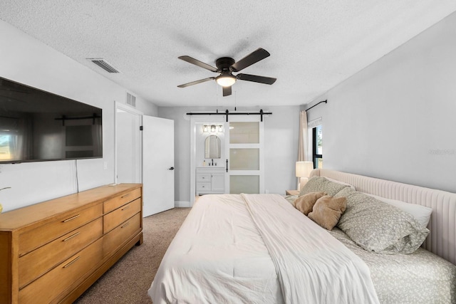 carpeted bedroom featuring ceiling fan, a barn door, and a textured ceiling