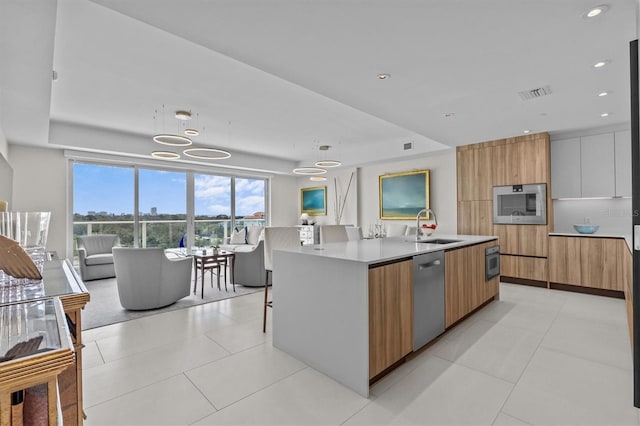 kitchen with decorative light fixtures, dishwasher, sink, white cabinets, and a large island