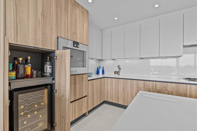 kitchen featuring wine cooler, light brown cabinetry, white cabinetry, and stainless steel gas stovetop