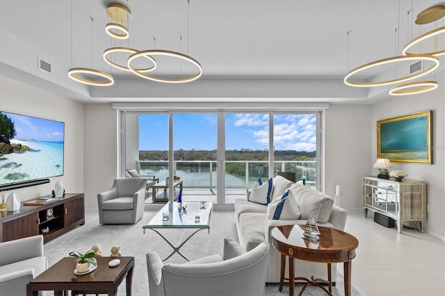 living room with a water view and a tray ceiling