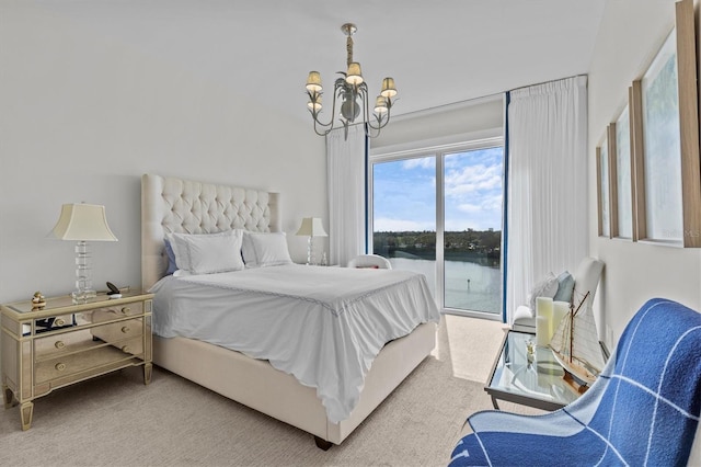 carpeted bedroom featuring access to exterior, a chandelier, and a water view