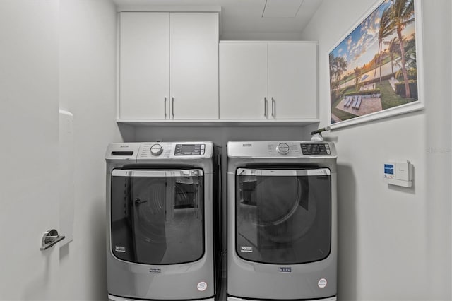 clothes washing area featuring independent washer and dryer and cabinets