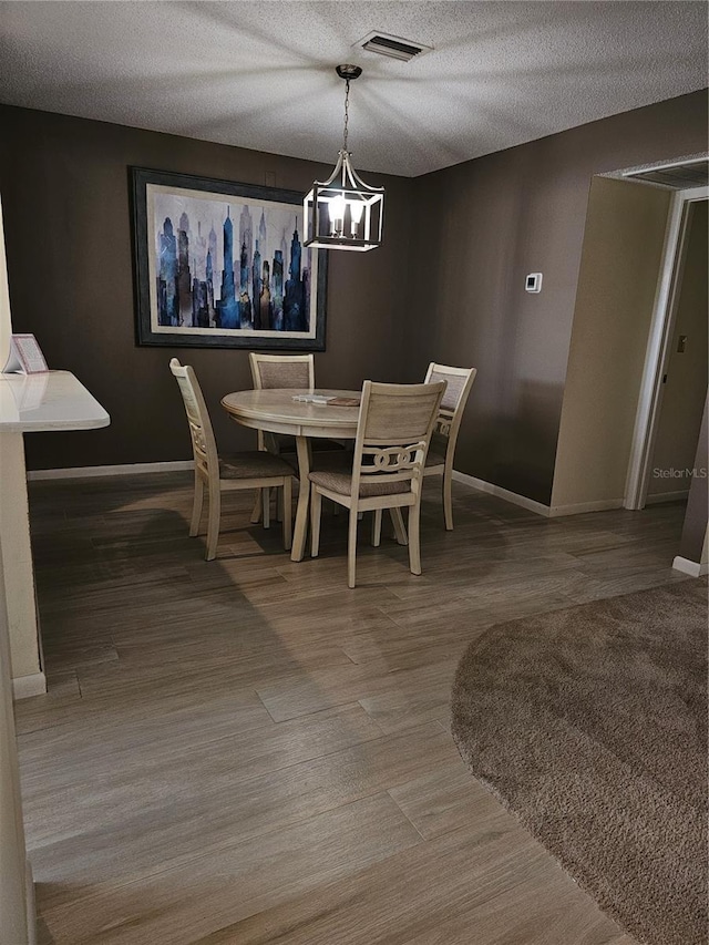 dining room with wood-type flooring and a textured ceiling