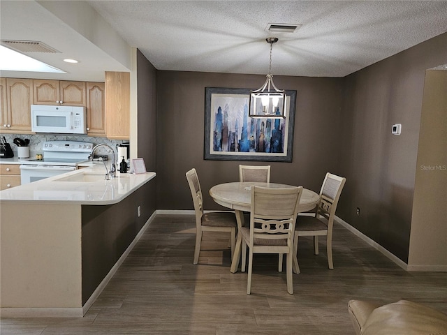 dining area featuring sink, dark wood-type flooring, and a textured ceiling