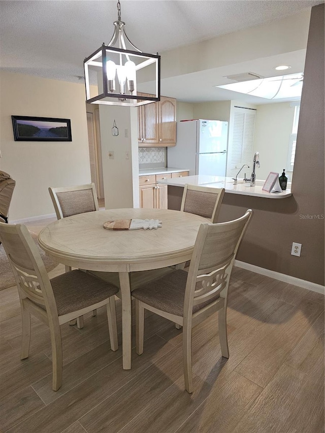 dining area with wood-type flooring, sink, and a chandelier