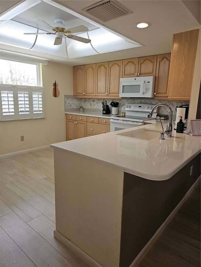 kitchen with backsplash, ceiling fan, kitchen peninsula, white appliances, and light hardwood / wood-style flooring