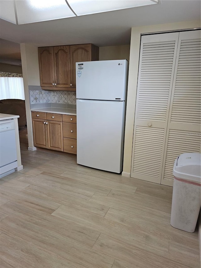 kitchen featuring tasteful backsplash, white appliances, and light hardwood / wood-style flooring