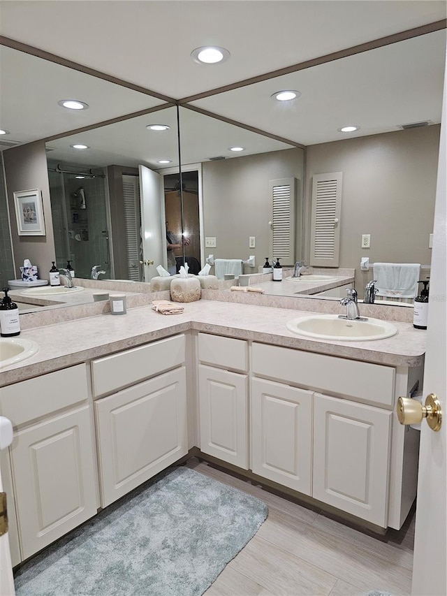 bathroom featuring a shower with door, vanity, and wood-type flooring