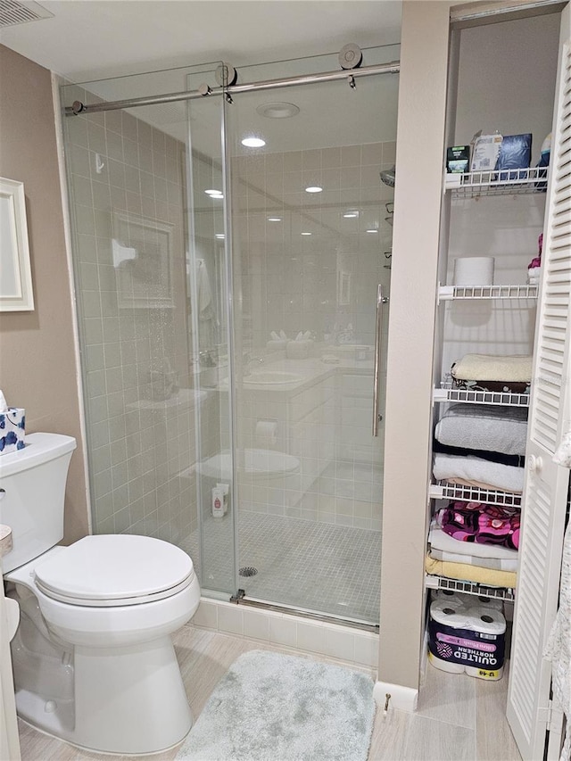 bathroom with a shower with door and toilet