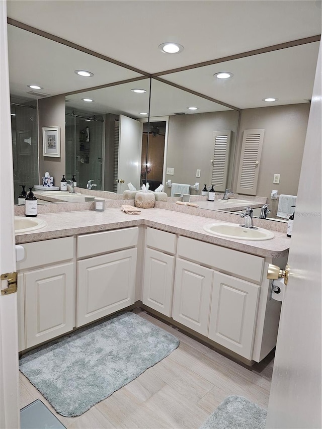 bathroom featuring a shower with door and vanity