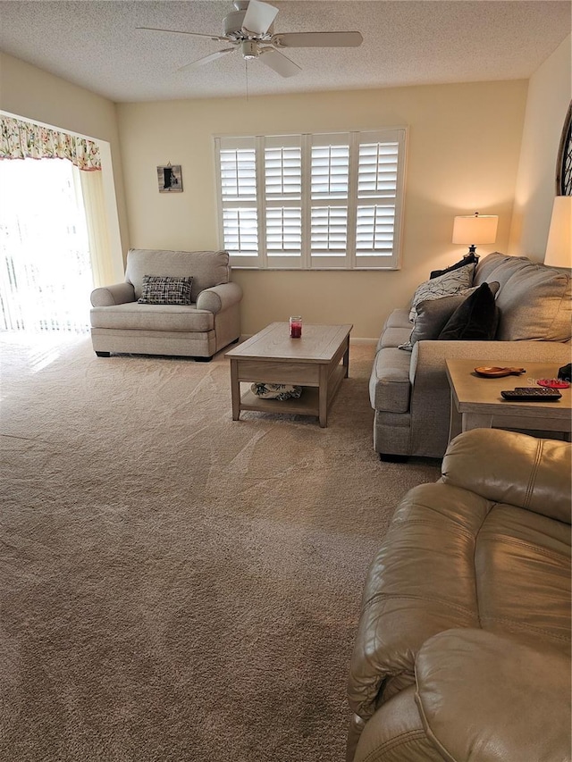 carpeted living room featuring ceiling fan and a textured ceiling