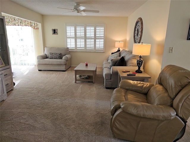 living room featuring ceiling fan, light colored carpet, and a textured ceiling