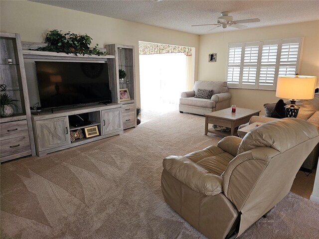 carpeted living room featuring ceiling fan and a textured ceiling