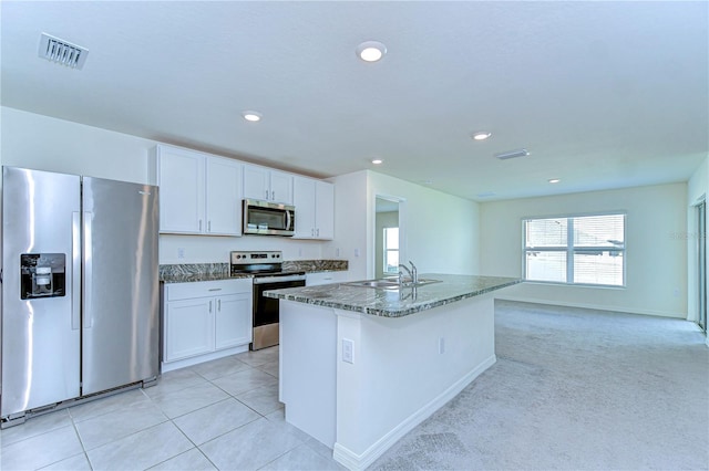 kitchen with visible vents, appliances with stainless steel finishes, dark stone countertops, white cabinetry, and a sink