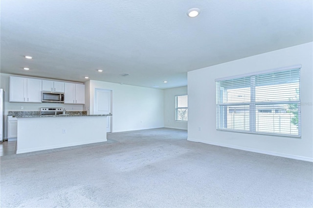 unfurnished living room with baseboards and recessed lighting