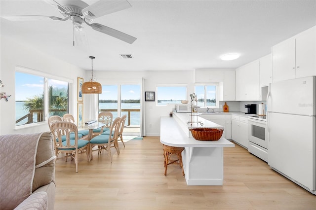 kitchen featuring white appliances, white cabinets, decorative light fixtures, a water view, and light countertops