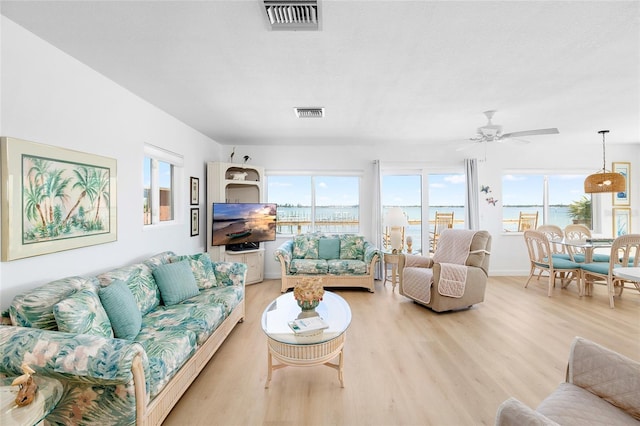 living area featuring light wood-style floors, visible vents, baseboards, and a ceiling fan