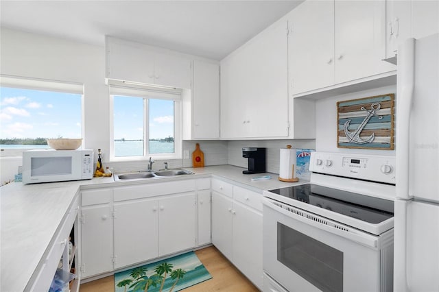 kitchen featuring tasteful backsplash, light countertops, white cabinetry, a sink, and white appliances