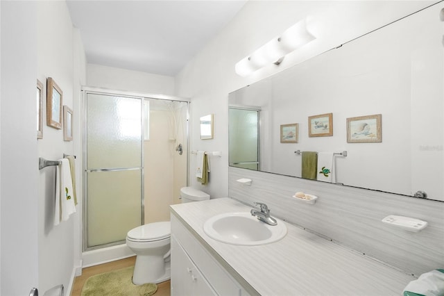 full bathroom featuring a stall shower, vanity, and toilet