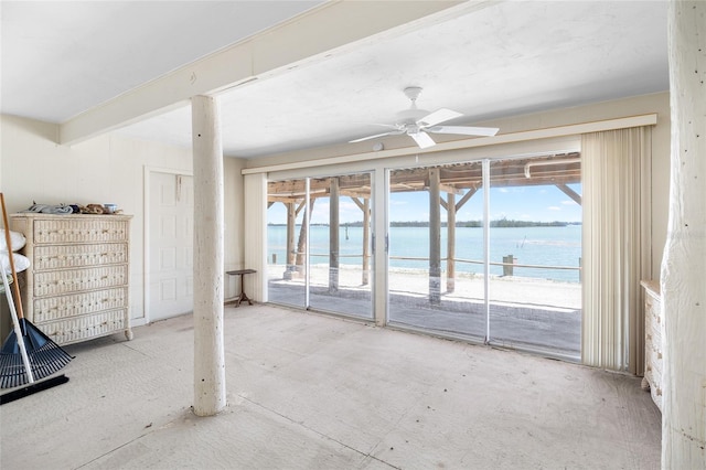 empty room featuring a water view, a view of the beach, a ceiling fan, and a wealth of natural light