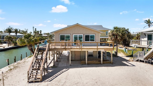 rear view of house featuring driveway and a deck with water view