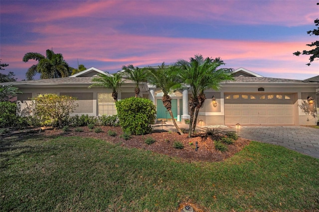 view of front facade with decorative driveway, a front lawn, and stucco siding