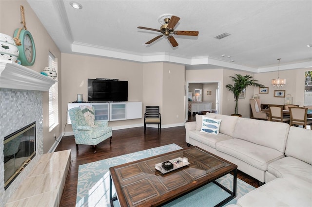 living area featuring baseboards, visible vents, a tiled fireplace, ornamental molding, and wood finished floors