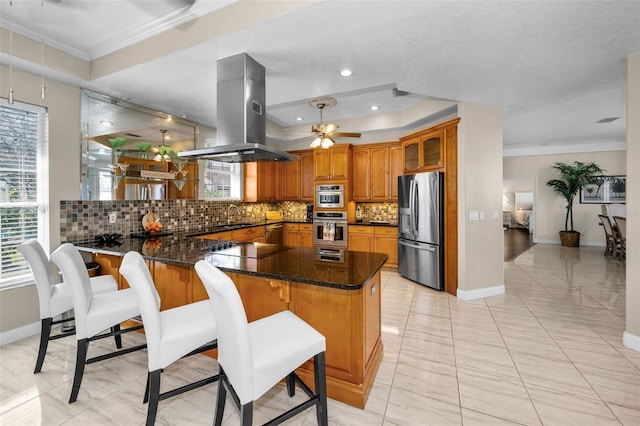 kitchen featuring appliances with stainless steel finishes, brown cabinets, glass insert cabinets, a peninsula, and island exhaust hood