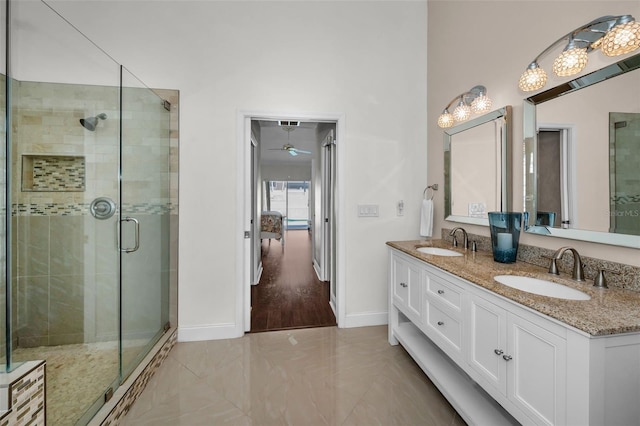 bathroom with a stall shower, a sink, baseboards, and double vanity