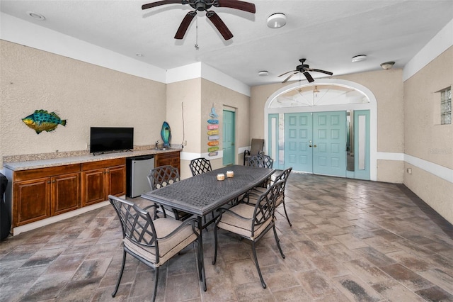 dining space featuring a textured wall and a ceiling fan