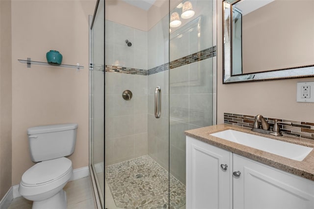 bathroom with toilet, vanity, baseboards, decorative backsplash, and a stall shower