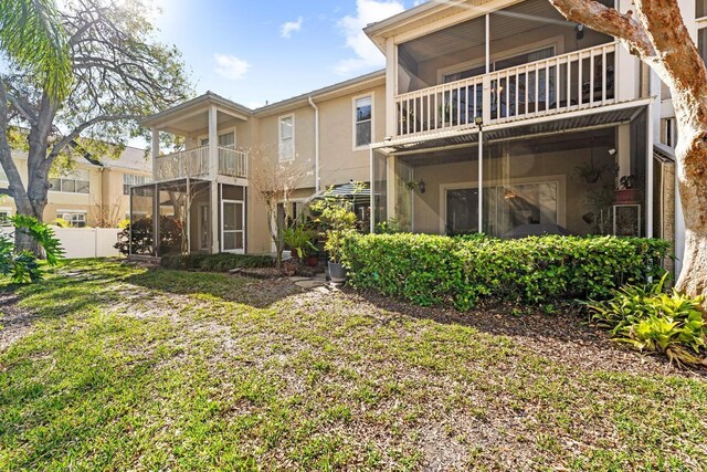 rear view of property featuring a balcony and a yard