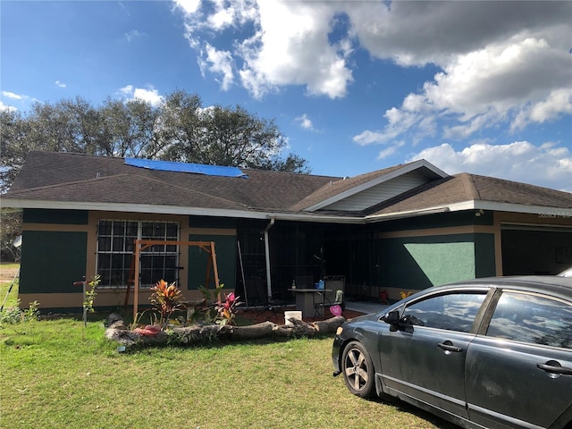 exterior space featuring a garage, a shingled roof, and a lawn