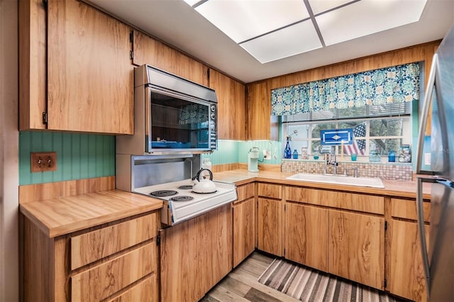 kitchen with light wood finished floors, light countertops, a sink, and stovetop