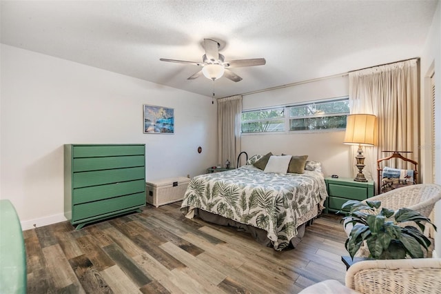 bedroom with a ceiling fan, a textured ceiling, baseboards, and wood finished floors