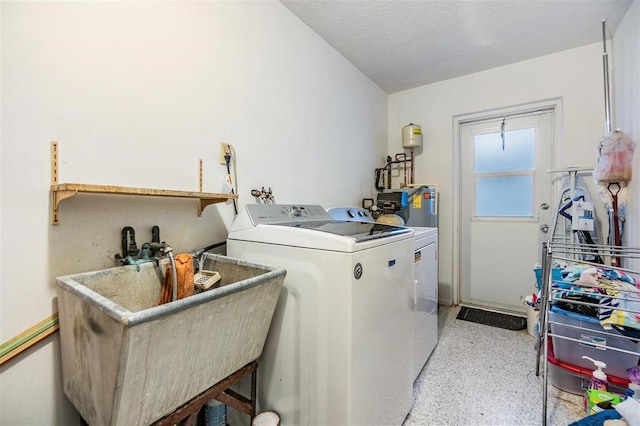 laundry room with washing machine and dryer, electric water heater, a sink, a textured ceiling, and laundry area