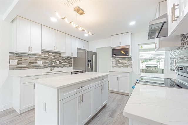 kitchen featuring a kitchen island, pendant lighting, white cabinetry, sink, and stainless steel appliances