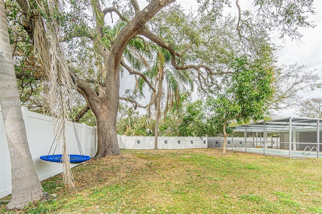 view of yard featuring a fenced in pool and glass enclosure