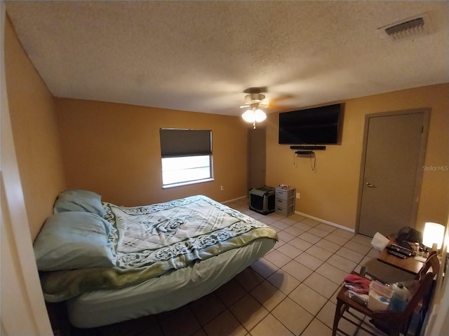 tiled bedroom with ceiling fan and a textured ceiling