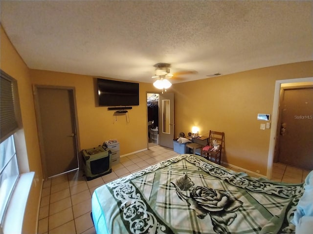 tiled bedroom with ceiling fan, a spacious closet, a closet, and a textured ceiling