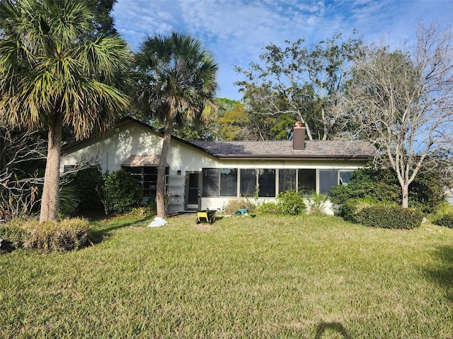 rear view of house with a chimney and a lawn