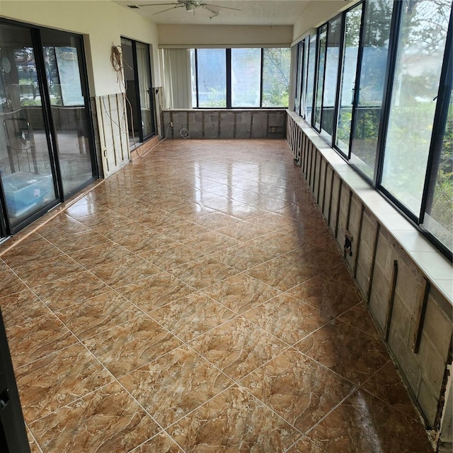 unfurnished sunroom featuring ceiling fan